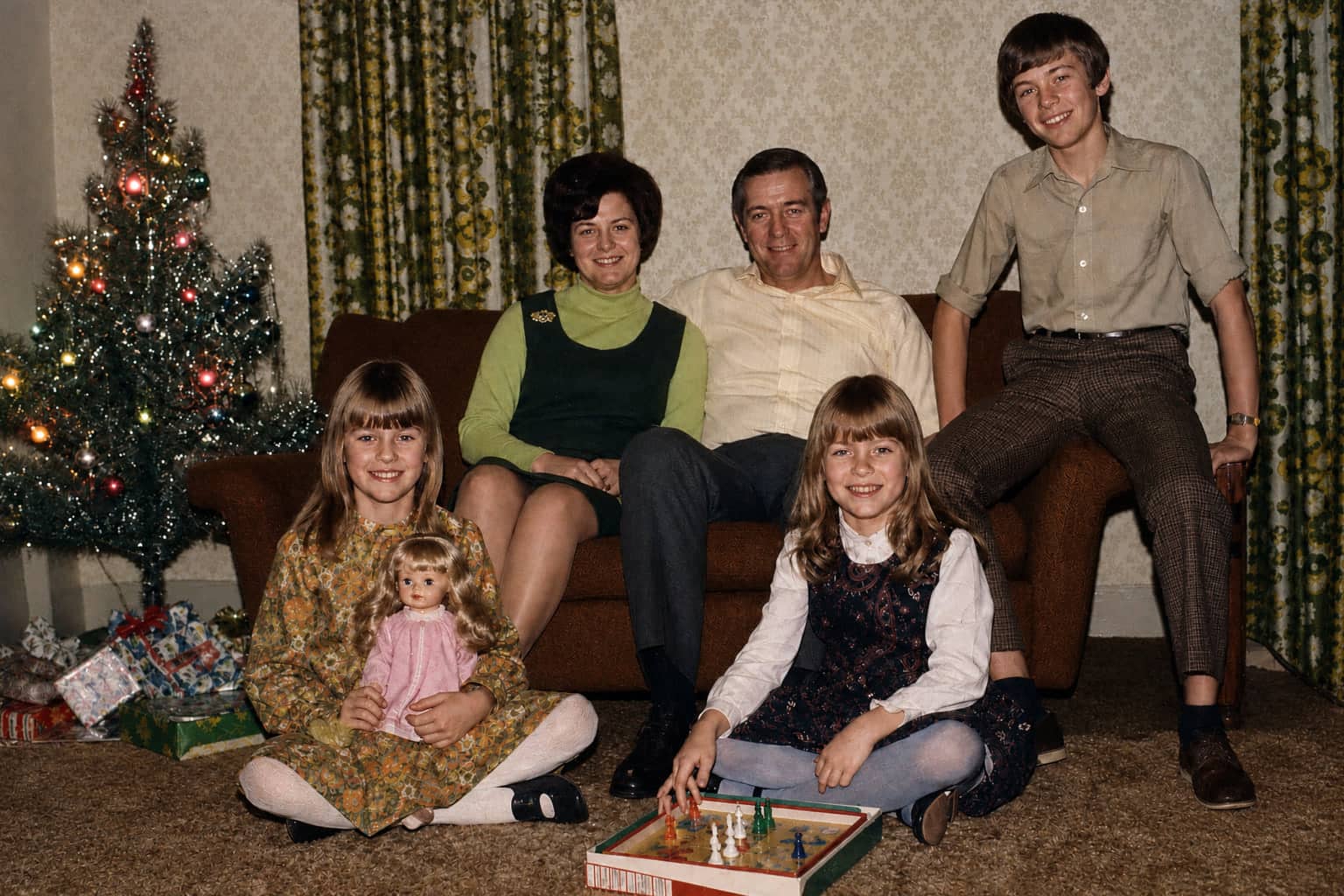 The same living room photo after restoration: creases repaired, colour back, the family unchanged.