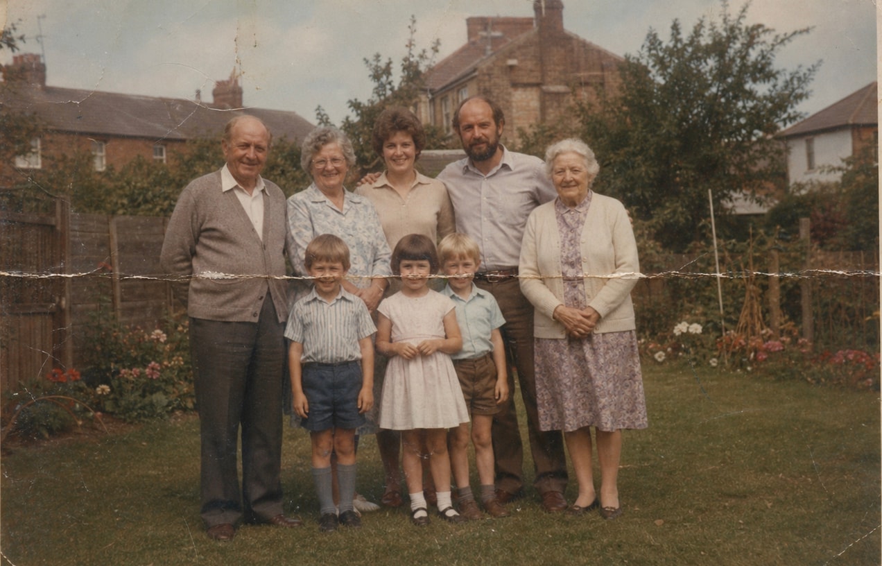 Faded family portrait before restoration with creases and worn color.